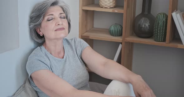 Resting Smiling Elderly Woman Reclining on a Comfy Sofa Stretching Calm Meditating