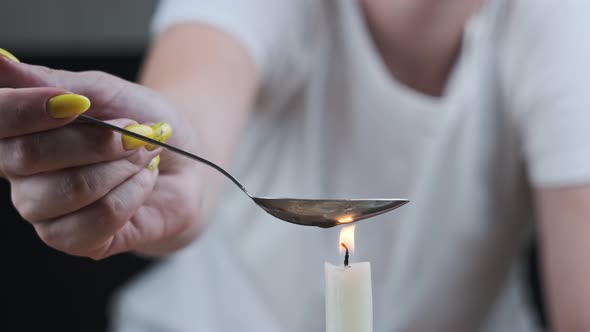 Woman Drug Addict Cooking Drugs in Spoon on Candle Flame