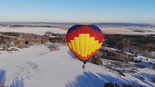 People Fly on a Big Bright Balloon Over the Winter Forest alt