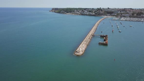 Aerial view of breakwater and harbour of Brixham, England. Boats are docked off shore.