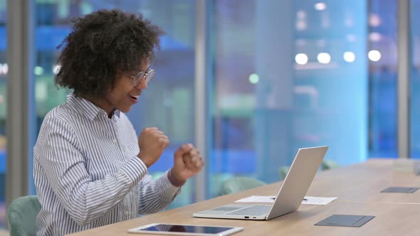 Excited African Businesswoman Celebrating Success on Laptop in Office 