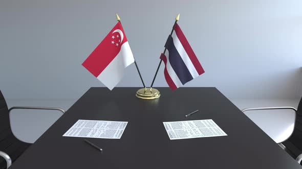 Flags of Singapore and Thailand and Papers on the Table