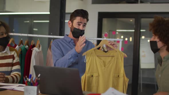 Mixed race clothes designers having video call wearing face masks