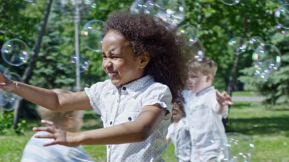 Happy African Girl Catching Soap Bubbles at Kids Party in Park alt