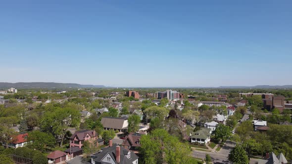 Drone view over midwest neighborhood in summer with bluffs and blue sky in horizon.