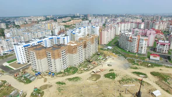 Flying over the construction site with a bird's eye in a city. New modern houses are building