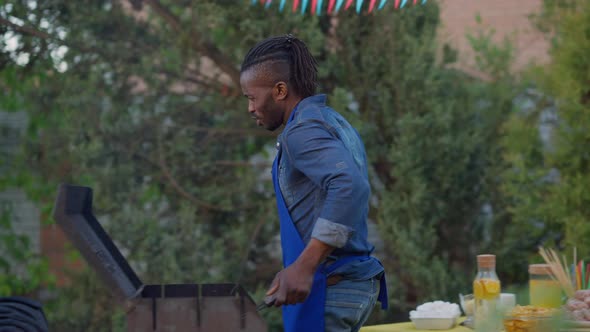 Live Camera Follows Serious African American Man Checking Bbq Grill and Walking to Busy Caucasian