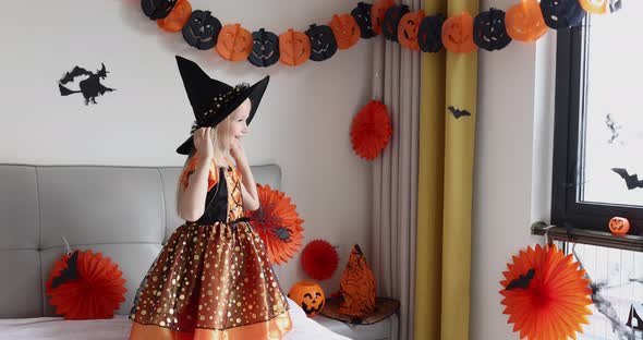 Cute Caucasian Little Girl with Blonde Hair Seven Years Old in Witch Dress and Hat Having Fun and