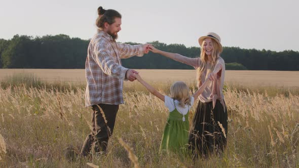Happy Family Having Fun Outdoors Holding Hands Playing in Wheat Field