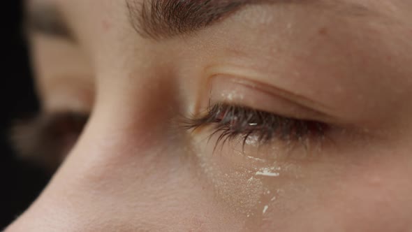 Closeup of Crying Brown Eyes Watery Eye of Young Woman and Wet Eyelashes Shooting of Tear Rolling