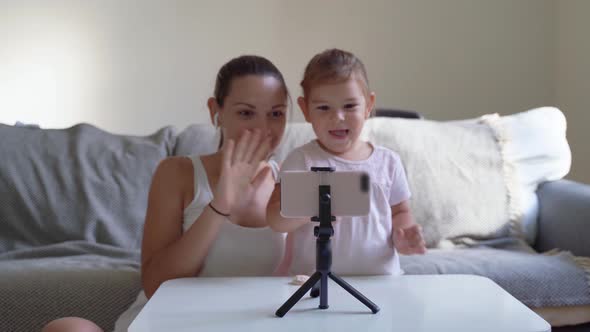 Mother with Child Streaming Online Video of Unboxing Clothes. Influencer Occupation, Mommy Blog