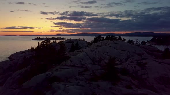 Flying Low over Rocky Pine Tree Island in Big Lake just after Sunset, Drone Aerial Wide Dolly In. Co