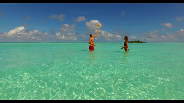 Family of two suntan on relaxing resort beach vacation by clear lagoon with white sandy background o