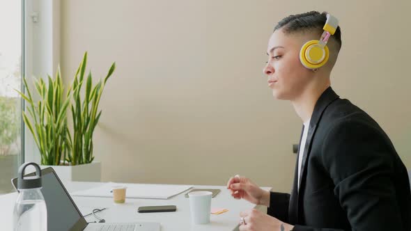 Businesswoman using laptop and headphones in office