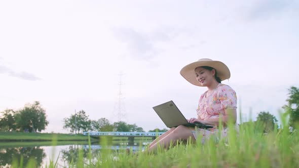 Adult woman sitting on lawn working with computer. Freedom concept when working remotely.