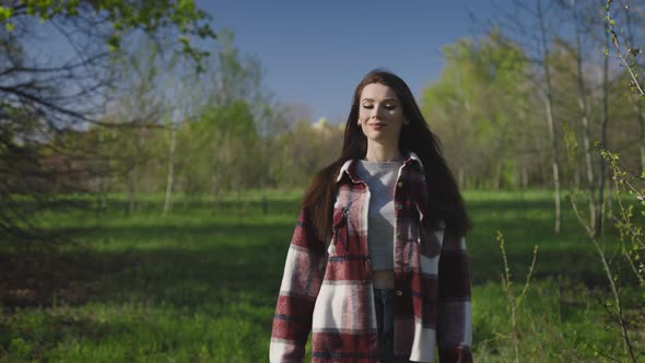 A Beautiful and Carefree Young Woman Walks in the Park in Spring