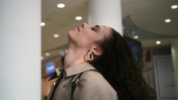 A Girl Adjusts Her Hair in a Shopping Mall