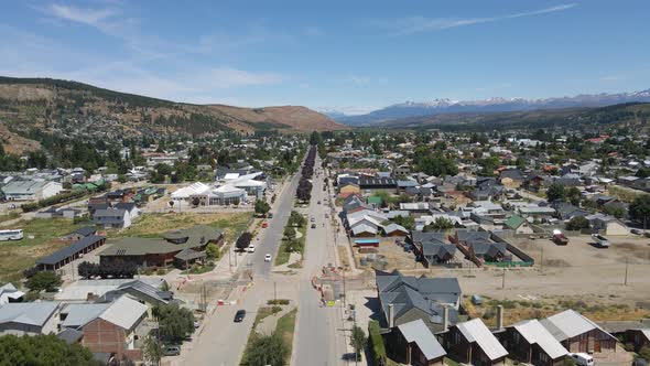 Dolly in flying over Esquel city main street with Andean mountains in background, Patagonia Argentin