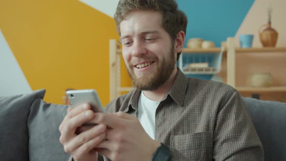 Slow Motion of Handsome Guy Using Smartphone Texting in Modern Apartment