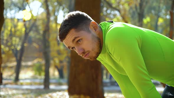 Handsome Sportsman Breathing Hard after Jogging in Autumn Park