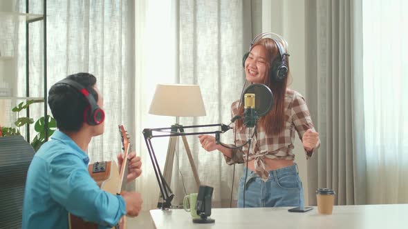 Young Asian Woman Singing While Man Playing The Guitar During Online Livestream In Podcast Studio