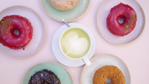 Top View of Spinning Image of Matcha Latte Surrounded By Colorful Donuts. 