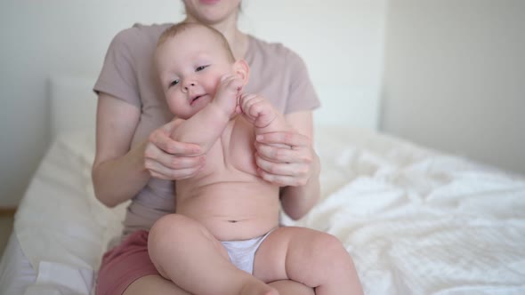 Cute Infant Toddler Boy Learns to Walk First Steps on Bed and Playing with Mother Early in Morning