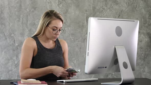 Young Woman Sit and Counting Money in the Office