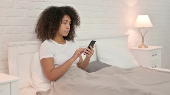 Smartphone Use By Young African Woman in Bed