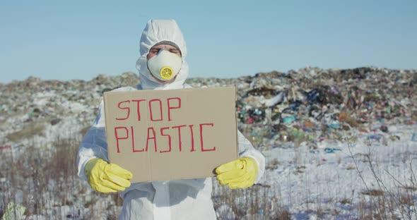 Man Wore in Protective Suit Show Protest Sign "Stop Plastic" at Plastic Landfill
