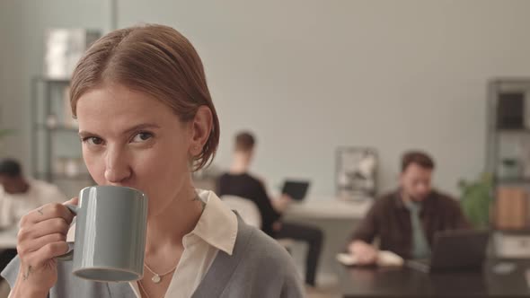 Woman Drinking Coffee Posing in Office
