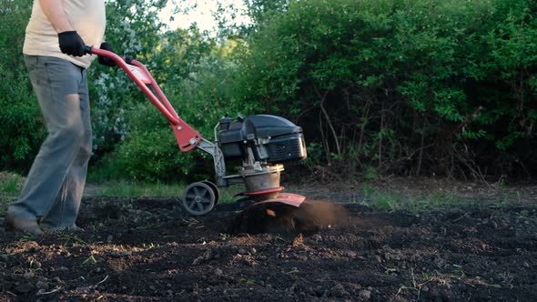 Man Plows the Ground with Motor Cultivator