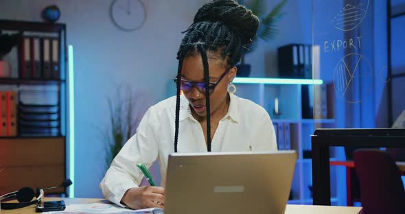 Businesswoman in Glasses Working with Papers and Computer Information in Evening Office