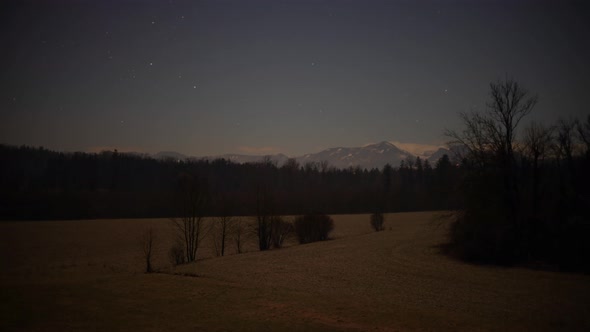 Nighttimelapse with Stars, Mountains, an Forest and Clouds/Fog