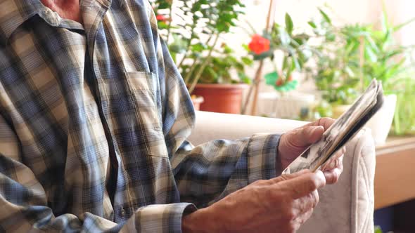 in the hands of an elderly man old family photos. a pensioner at home sitting looking at the photo a