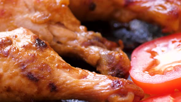 close-up pieces of appetizing fried meat rotate.grilled chicken legs, tomatoes, greens macro.selecti