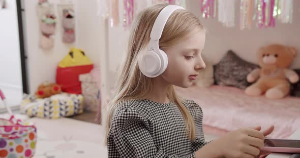 The 7Yearold Girl in the Children's Room with Headphones and Using Smartphone