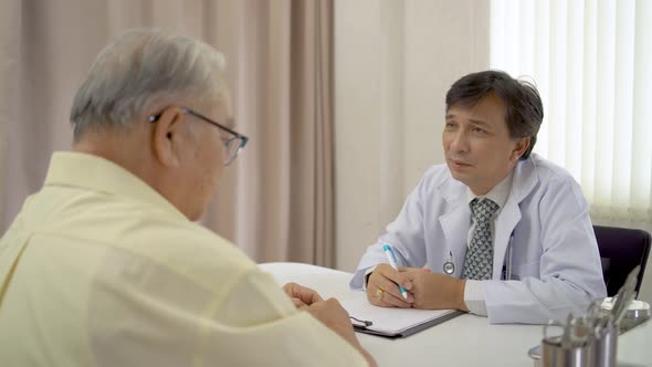 Male doctor physician caregiver taking notes at consultation with elderly patient, about health care