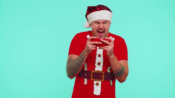 Worried Man in New Year Tshirt and Hat Enthusiastically Playing Racing Video Games on Mobile Phone