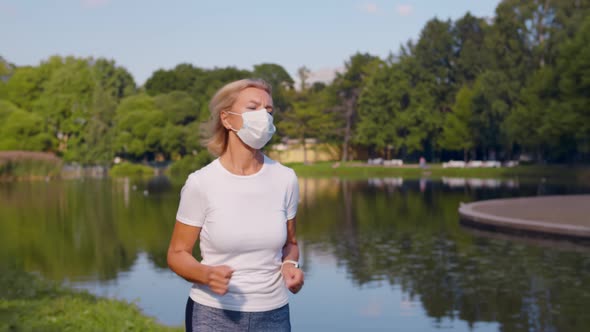 Senior Sporty Woman Wearing Safety Mask Jogging in Summer Park