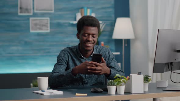 Black Man in Living Room Enjoying Social Media Content on Phone