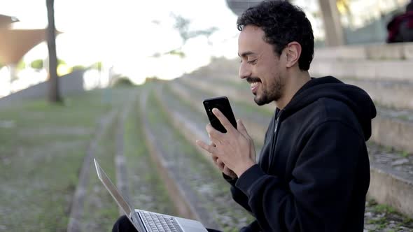 Happy Man Using Laptop and Smartphone