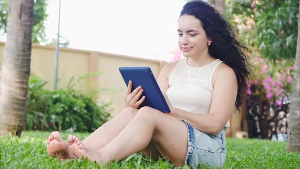 European Woman Makes Use of a Tablet or Phone with a Smartphone, Leafs or Texting with Her Finger