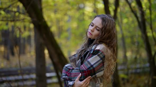 Portrait of a Woman with Curly Hair and a Plaid Coat in an Autumn Park
