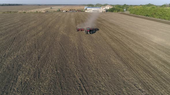 Farm Tractor with Plough Cultivates Agrarian Land on Field Before Sowing Agricultural Crops