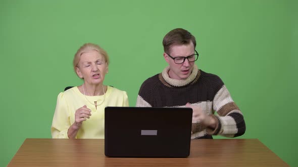 Senior Businesswoman and Young Handsome Man Using Laptop and Getting Bad News Together