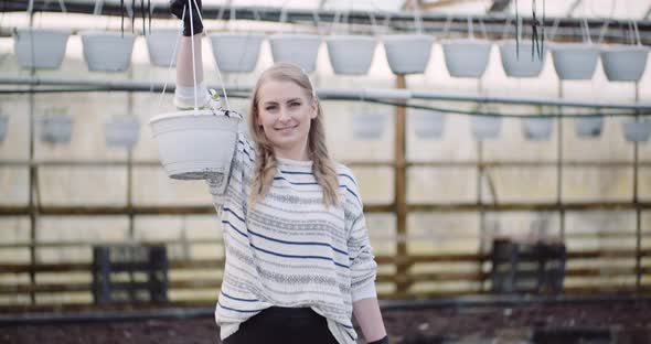 Agriculture - Female Gardener Holding Two Flowers Pots in Greenhouse