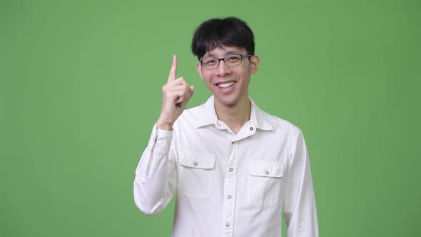 Young Happy Asian Businessman Smiling While Pointing Up