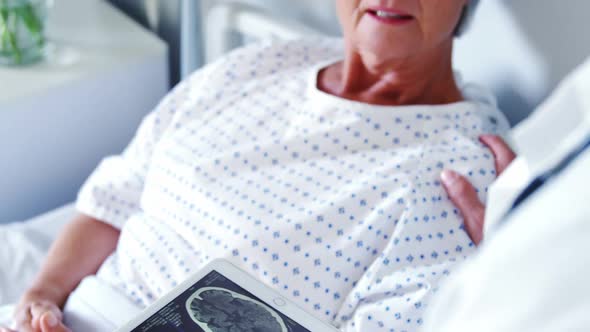 Male doctor discussing medical report with senior woman on digital tablet