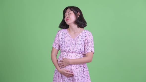 Happy Asian Pregnant Woman Relaxing with Eyes Closed